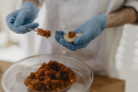 A closeup shot of a chef in blue gloves preparing appetizers with meat