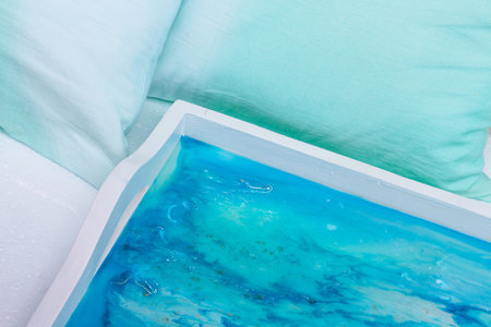 A high angle closeup shot of a white tray with epoxy resin art with blue alcohol inksの写真素材