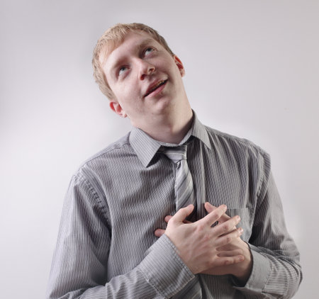 A view of a caucasian male wearing a grey shirt with his hands on his chest - concept: thankfulの写真素材