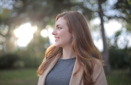 A shallow focus shot of a caucasian female in a park while smiling and looking away