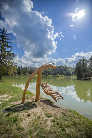 A wooden swing over Lake Bloke in Nova Vas, Slovenia on a sunny dayの写真素材