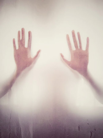 A vertical shot of a blurry steamed window with a pair of hands seen from the other side-concept:scaryの写真素材