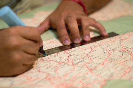 A closeup view of a male sketching a line with a blue highlighter and ruler on the world map