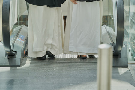 The feet of two people getting on the escalator under the lights