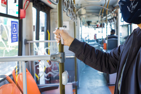 A closeup shot of a young male in a mask holding handrail pole in an empty transport- transport while the quarantine conceptの写真素材