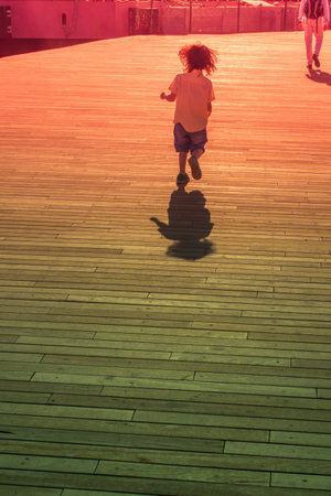 A vertical shot of a child running on a wooden surfaceの写真素材