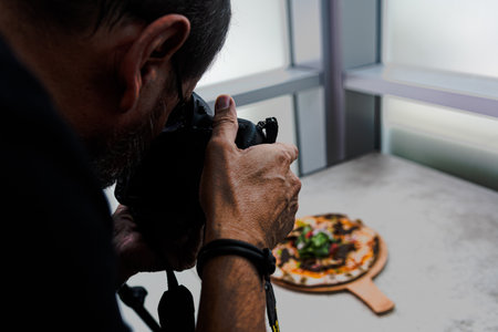A high angle shot of a person taking a photo of a pizza on the table
