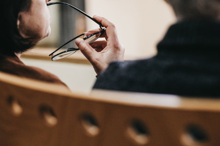 A close up shot of a middle aged woman holding her glasses and thinkingの写真素材