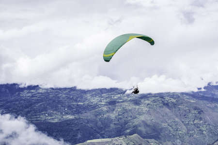 A person parasailing in the mountains on a gloomy day