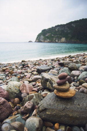 A vertical closeup shop of stones on a beach with a beautiful sea view on the background