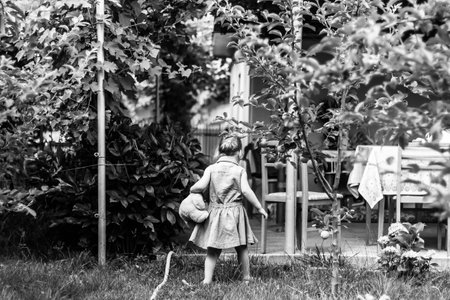 A grayscale back view of a child playing in the gardenの写真素材