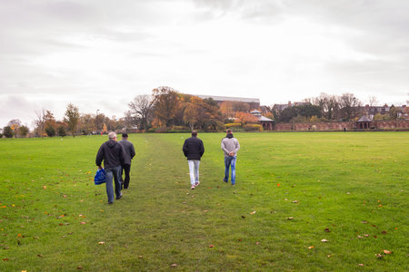 A bunch of people walking in the park during a cloudy day