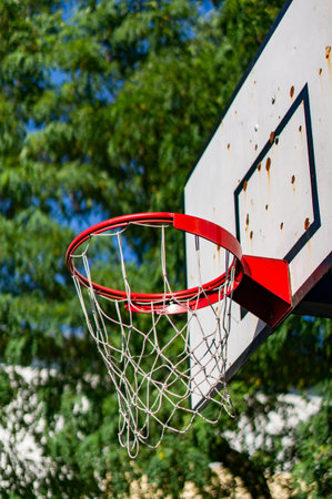 A vertical low angle shot of a basketball hoop with a blurred background