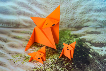 A closeup shot of three orange paper origamis with faces drawn on them on a patterned surface