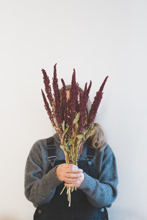 A blonde woman holding a big bouquet of lavenders in front of her face