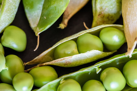 A closeup shot of fresh green pea seeds on black wooden background