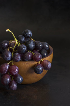 A closeup shot of the grapes in a bowl isolated on a black backgroundの写真素材