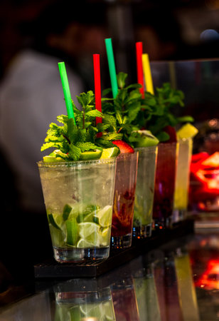 A vertical selective focus shot of fresh cocktails with colourful straws in the barの写真素材