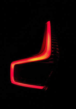 A closeup of a lit red tail light of a car against a dark backgroundの写真素材