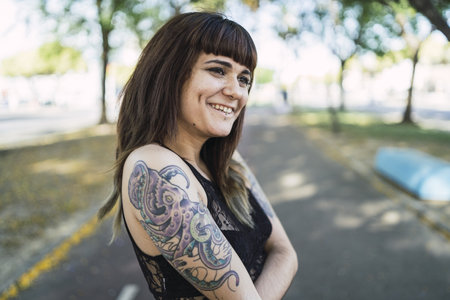 A young attractive Caucasian female with tattoos standing in the park making a cute faceの写真素材