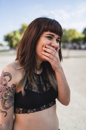 A young attractive Caucasian female with tattoos standing in the street and making a cute faceの写真素材