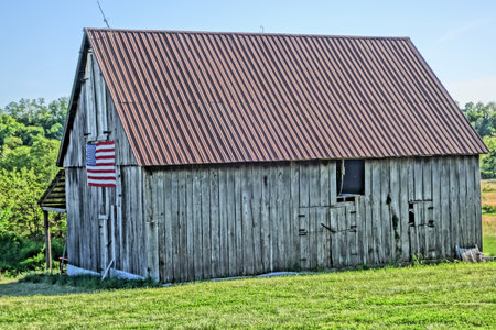 An old barn at Central Missouri with an American flag on a wooden wallの写真素材