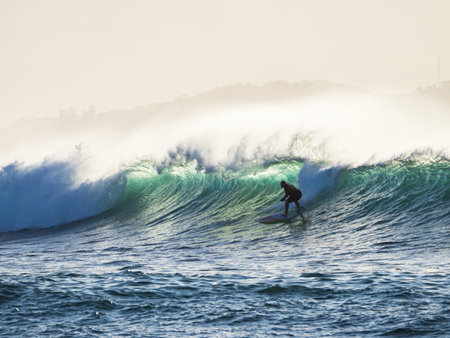 A silhouette of a man surfing in the wavy sea - perfect for backgroundの写真素材