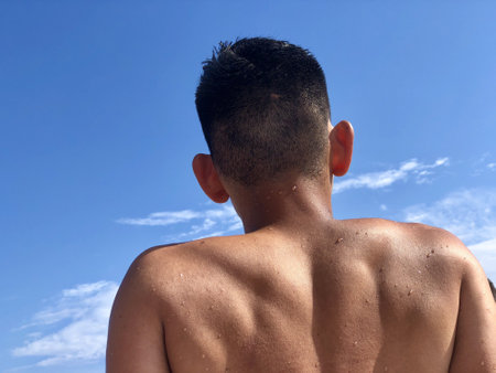 A caucasian male relaxing under the warm sun with the blue sky on the backgroundの写真素材