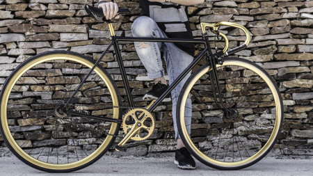 A closeup shot of a young male with a modern bicycle on a brick wall background