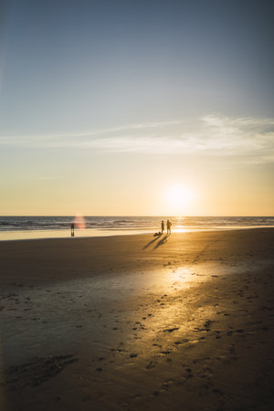 A beautiful seascape of the sunset over the coastline and some people walkingの写真素材