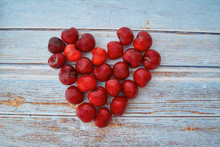 A closeup shot of heart-shaped juicy cherries on wooden backgroundの写真素材