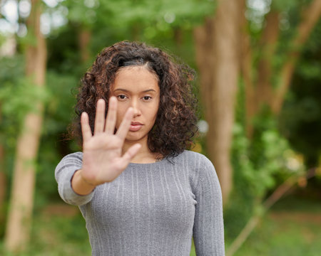 A selective focus shot of a serious determined female showing stop sign