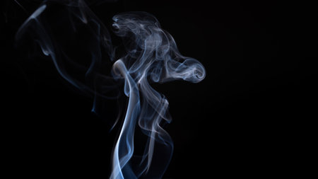 A white smoke creating abstract shapes on a black backgroundの写真素材