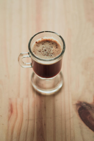 A high angle shot of a cup of Cappucino on a wooden surface