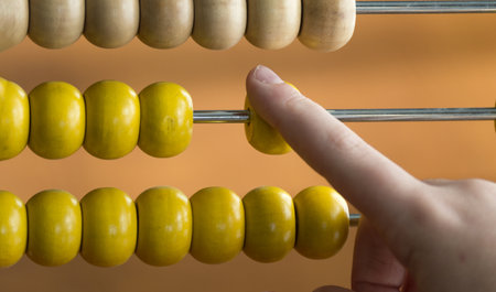 A closeup shot of a child hand used a wooden abacus at homeの写真素材