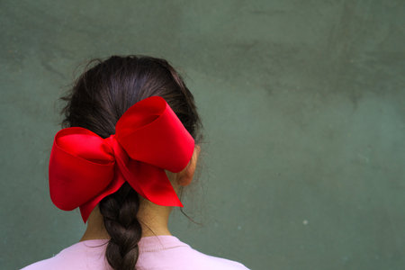 A young Siberian girl with a red ribbon on its braided hair isolated on a gray background  -...