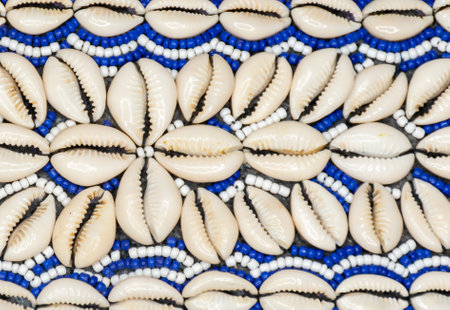 A closeup of a stringed white and blue strings and cowrie shells forming a patternの写真素材