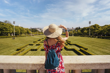 A young female tourist in a red floral dress in The Eduardo VII Park under the sunlight in Portugalの写真素材