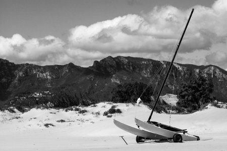 A grayscale shot of a sail canoe on wheels in snowy mountainsの写真素材