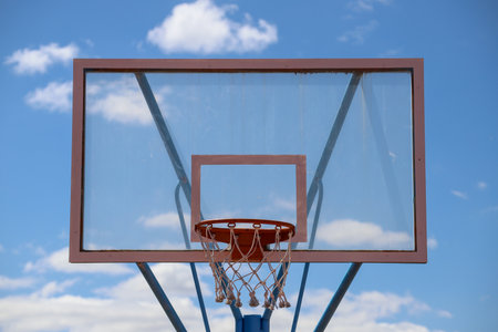A closeup of a basketball hoop in a field under the sunlight and a blue sky