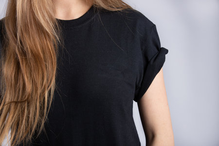 A young female wearing a black short sleeve t-shirt with a white wall in the backgroundの写真素材