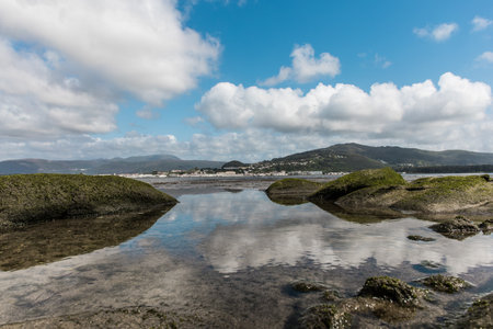 The rocks sticking out of the water under the sky full of cloudsの写真素材