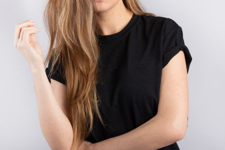 A young female wearing a black short sleeve t-shirt with a white wall in the backgroundの写真素材