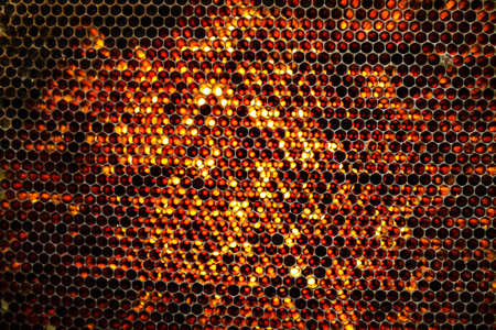 A metal mesh patterned surface with glowing yellow and orange lights