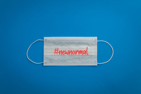 A closeup shot of a face mask with "new normal" writing on blue backgroundの写真素材