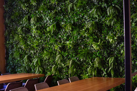 The empty wooden tables near the green plants outside the restaurant