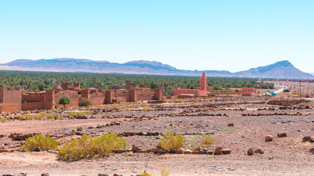The plains of Morocco featuring mud brick houses and vast greenery and mountains in the background