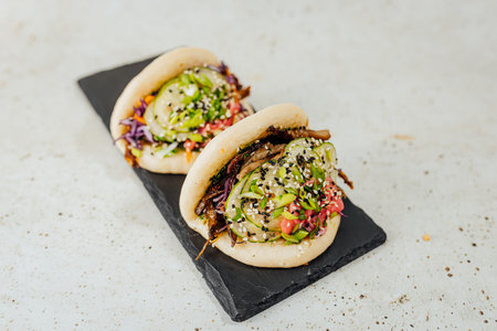 A closeup shot of a steamed bao bun with cucumber covered with sesame seedsの写真素材