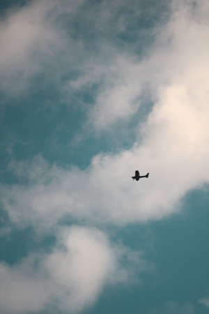 A vertical shot of an airplane in the cloudy sky