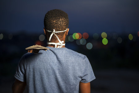 A back view of a young African American male in a protective face mask holding a shovelの写真素材